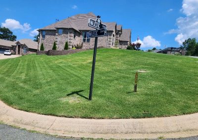 1333x616.jpeg.2e0387ebeacf4fc7b09c747eafd85d73 Well-manicured lawn with a house in the background, street sign for
