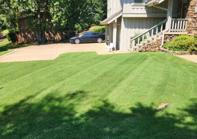 2000x924.jpeg.1f5c95d436a649fb84d9c141570d745e Lush, well-manicured lawn with striped grass patterns, residential home and driveway in Central Arkansas, showcasing APEX Lawn Care's professional lawn care services.