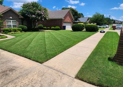 2000x924.jpeg.7bc70c9844d8420d9242faea64e1b9ad Lush green lawn with neatly striped grass, well-maintained shrubs, and a clear sidewalk, showcasing professional lawn care services by APEX Lawn Care in Little Rock, Arkansas.