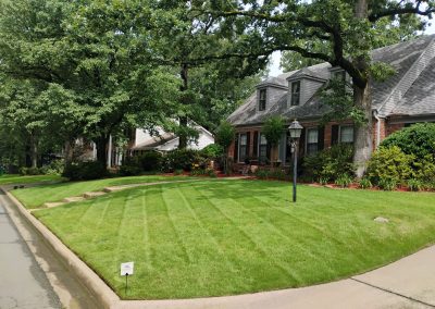 2040x1536.jpeg.8edd642a4c0541fab10f0a292959793b Lush green lawn with neatly striped grass, landscaped front yard of a suburban home in Central Arkansas, showcasing professional lawn care services by APEX Lawn Care.