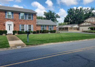 Suburban neighborhood with brick houses and well-manicured lawns. - Little Rock Lawn Care and Mowing Services by Apex Lawn Care Lawn care service by APEX Lawn Care showcasing a well-maintained green lawn in front of a brick house in Little Rock, Arkansas.