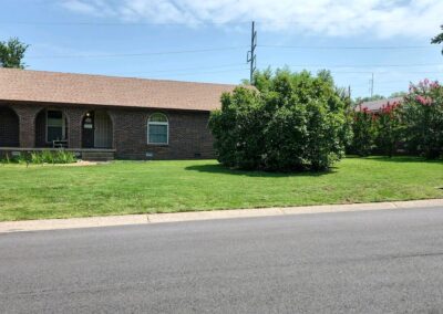 Single-story brick house with a well-maintained lawn and lush greenery on a sunny day. - Little Rock Lawn Care and Mowing Services by Apex Lawn Care Lawn care service showcasing a well-maintained green lawn and shrubbery in front of a brick home in Little Rock, Arkansas.