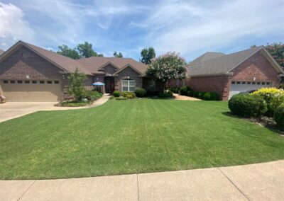 A single-story residential home with a well-maintained lawn and blooming trees under a clear blue sky is perfect for an employee. - Little Rock Lawn Care and Mowing Services by Apex Lawn Care Lush green lawn in front of residential property, showcasing professional lawn care services by APEX Lawn Care in Little Rock, Arkansas.