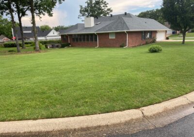 A single-story brick house with a screened porch and well-maintained lawn on a cloudy day. - Little Rock Lawn Care and Mowing Services by Apex Lawn Care Lawn care service showcasing a well-maintained green lawn surrounding a residential home in Little Rock, Arkansas, highlighting APEX Lawn Care's professional landscaping expertise.