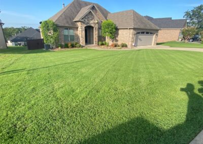 Well-manicured lawn in front of suburban house on a sunny day. - Little Rock Lawn Care and Mowing Services by Apex Lawn Care Well-maintained green lawn in front of a residential home, showcasing APEX Lawn Care services in Little Rock, Arkansas.