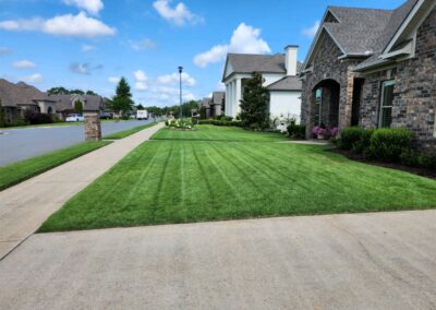 A well-manicured lawn in front of Little Rock Metro Area houses on a sunny day. - Little Rock Lawn Care and Mowing Services by Apex Lawn Care Lush green lawn with neatly striped grass, showcasing professional lawn care services in a residential area of Little Rock, Arkansas.