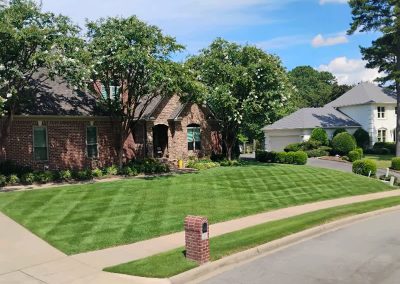 large-11 Lush, manicured lawn with distinct mowing patterns in front of a well-maintained brick home, showcasing APEX Lawn Care services in Central Arkansas.