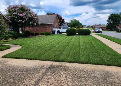 large-16 Lush, well-maintained lawn with striped mowing pattern, bordered by shrubs and trees, showcasing APEX Lawn Care's professional lawn care services in Central Arkansas.