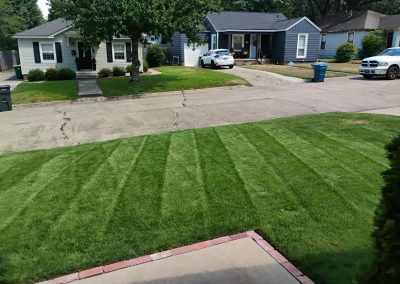original-4 Lush green lawn with neatly striped grass in front of residential homes, showcasing professional lawn care services by APEX Lawn Care in Little Rock, Arkansas.